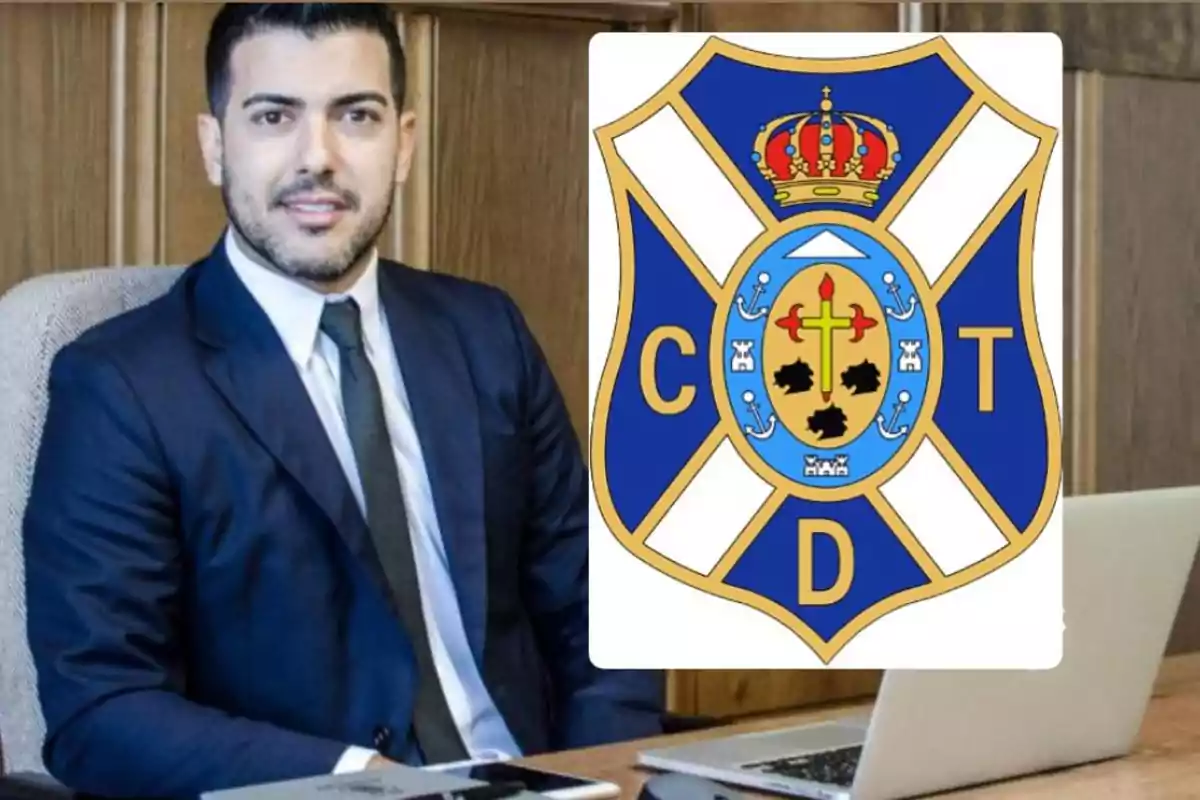 Un hombre con traje sentado en una oficina junto al escudo del Club Deportivo Tenerife.