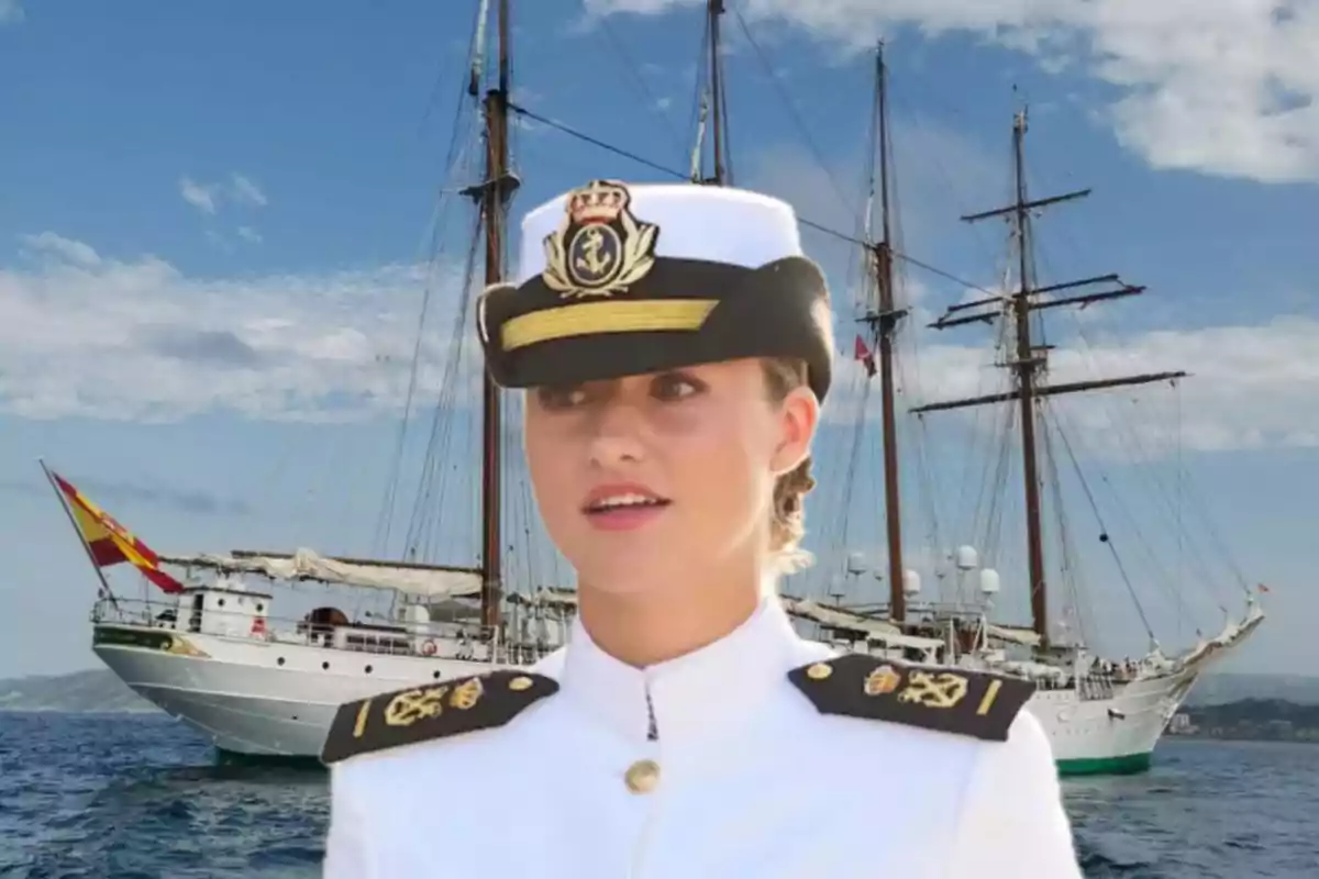 Una persona con uniforme naval blanco y gorra de oficial está frente a un gran velero en el mar, con el cielo azul y algunas nubes de fondo.