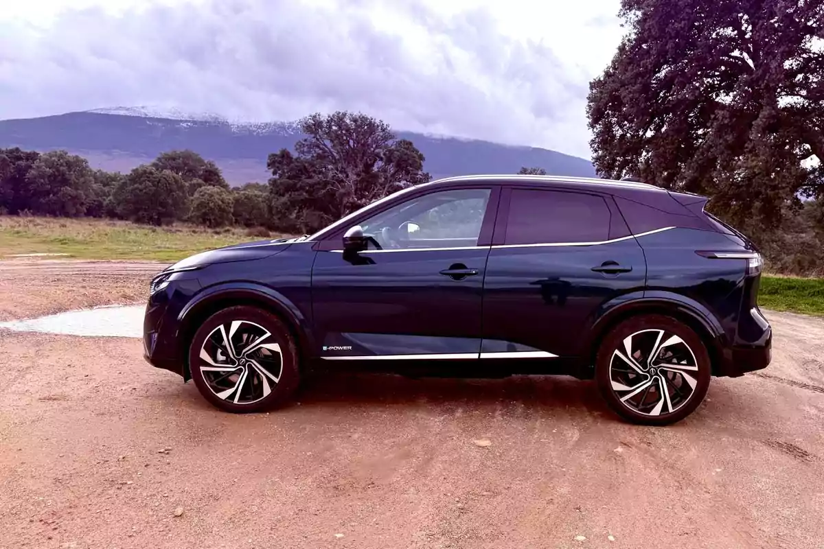 Un Nissan Qashqai e-POWER 2025 negro estacionado en un camino de tierra con un paisaje montañoso y árboles al fondo. Un Nissan Qashqai e-POWER 2025 negro estacionado en un camino de tierra con un paisaje montañoso y árboles al fondo.