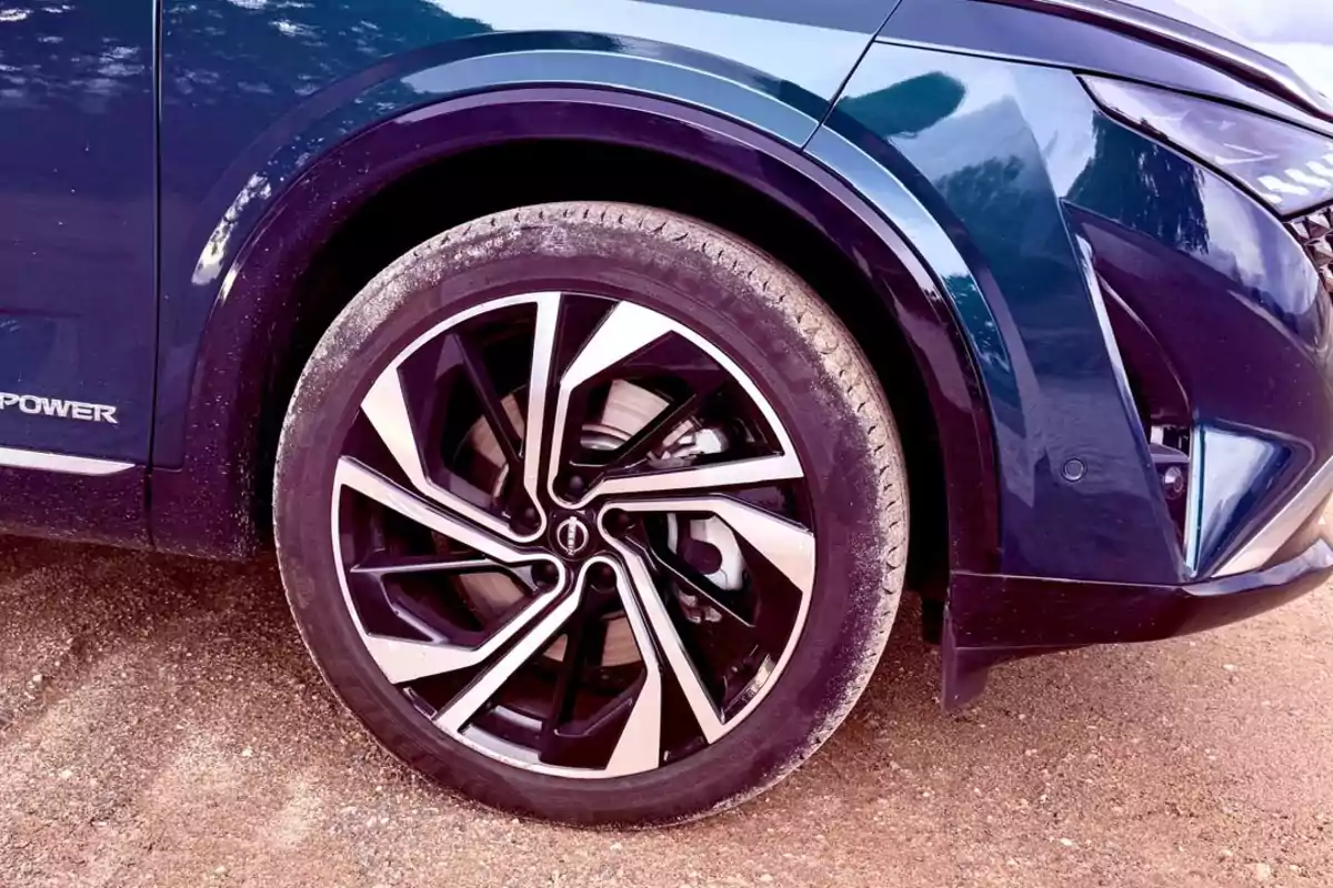Primer plano de la llanta de un Nissan Qashqai e-POWER 2025 azul sobre un camino de tierra. Primer plano de la llanta de un Nissan Qashqai e-POWER 2025 azul sobre un camino de tierra.