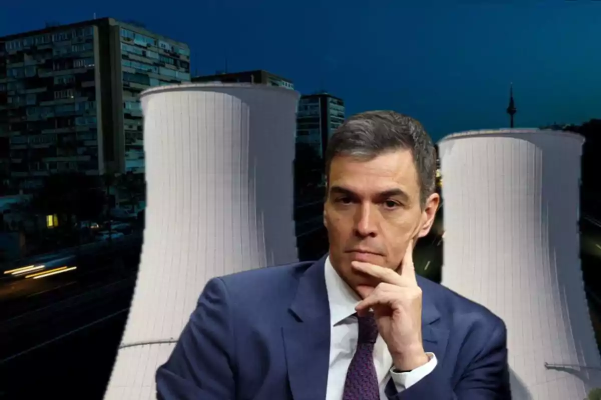 Un hombre en traje con expresión pensativa está superpuesto frente a dos torres de refrigeración de una planta industrial, con edificios residenciales al fondo en un entorno nocturno.