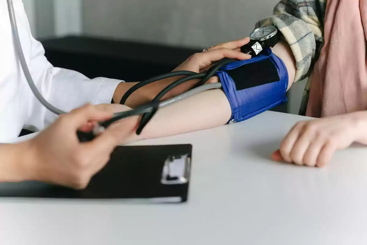 Persona tomando la presión arterial a otra con un esfigmomanómetro en una consulta médica