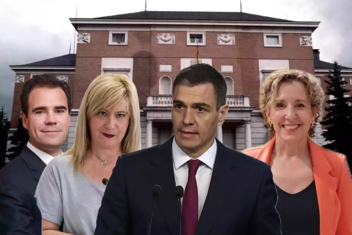 Cuatro personas posan frente a un edificio gubernamental de ladrillo rojo, con una bandera en el centro y cielo nublado de fondo.