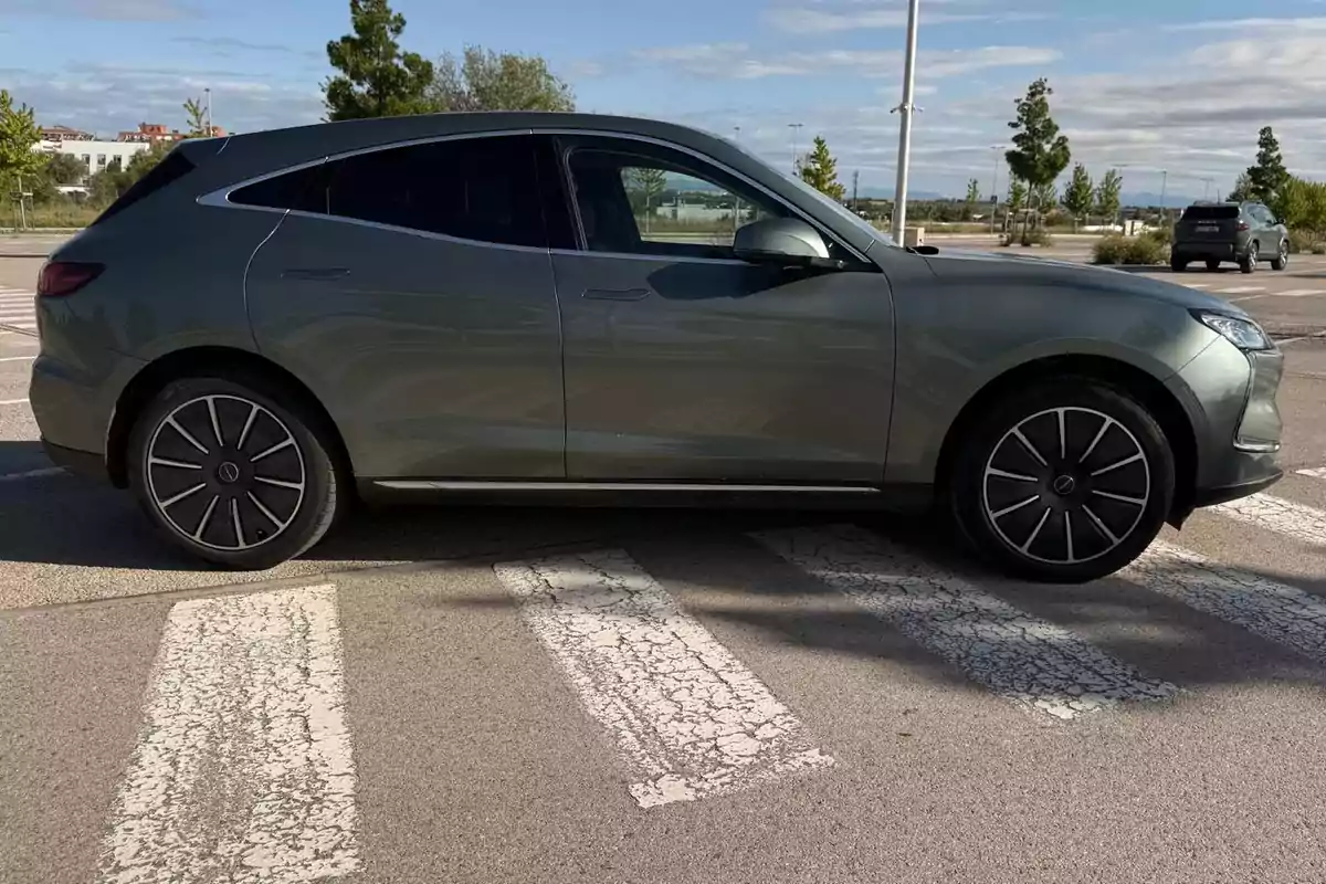 Un Seres 5 EV SUV gris estacionado sobre un paso de peatones en un aparcamiento al aire libre en un día soleado. Un Seres 5 EV SUV gris estacionado sobre un paso de peatones en un aparcamiento al aire libre en un día soleado.
