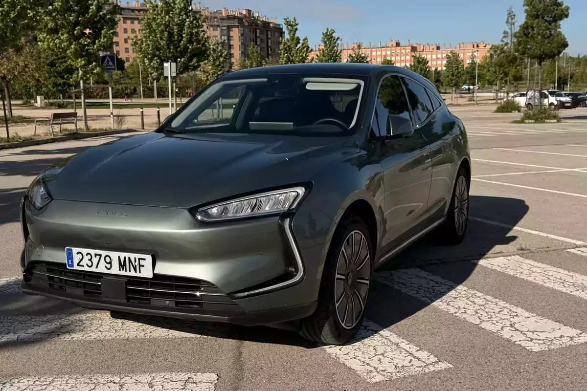 Seres 5 EV eléctrico de color gris estacionado en un aparcamiento al aire libre con edificios y árboles al fondo
