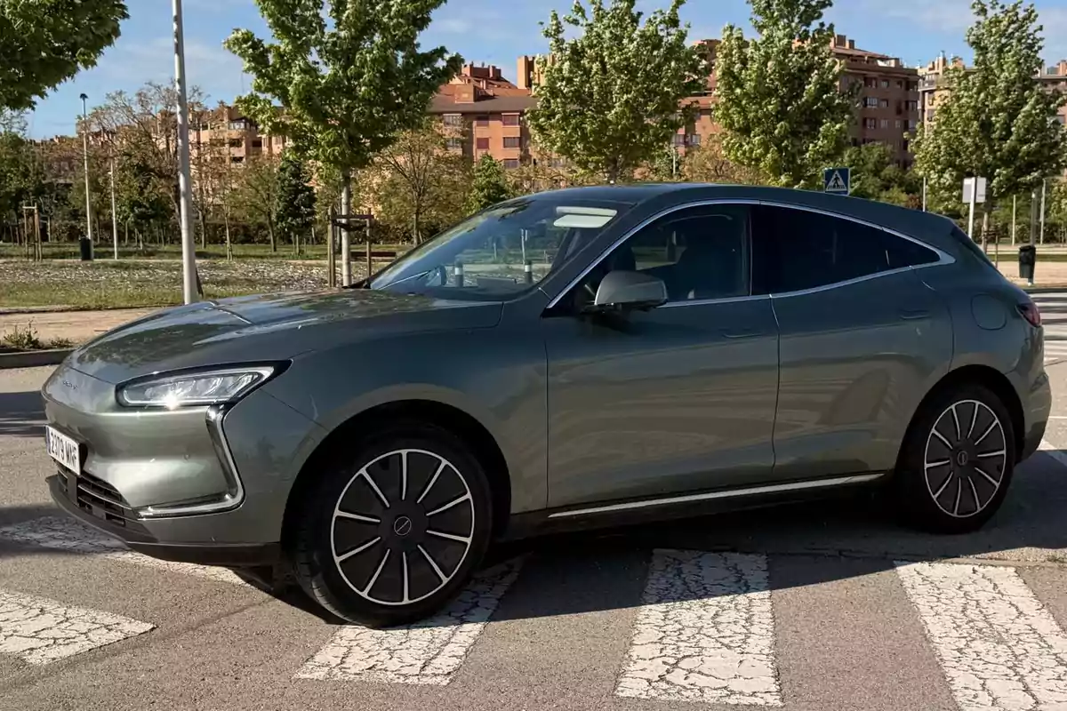 Coche SUV gris estacionado en una calle con árboles y edificios al fondo Coche SUV gris estacionado en una calle con árboles y edificios al fondo
