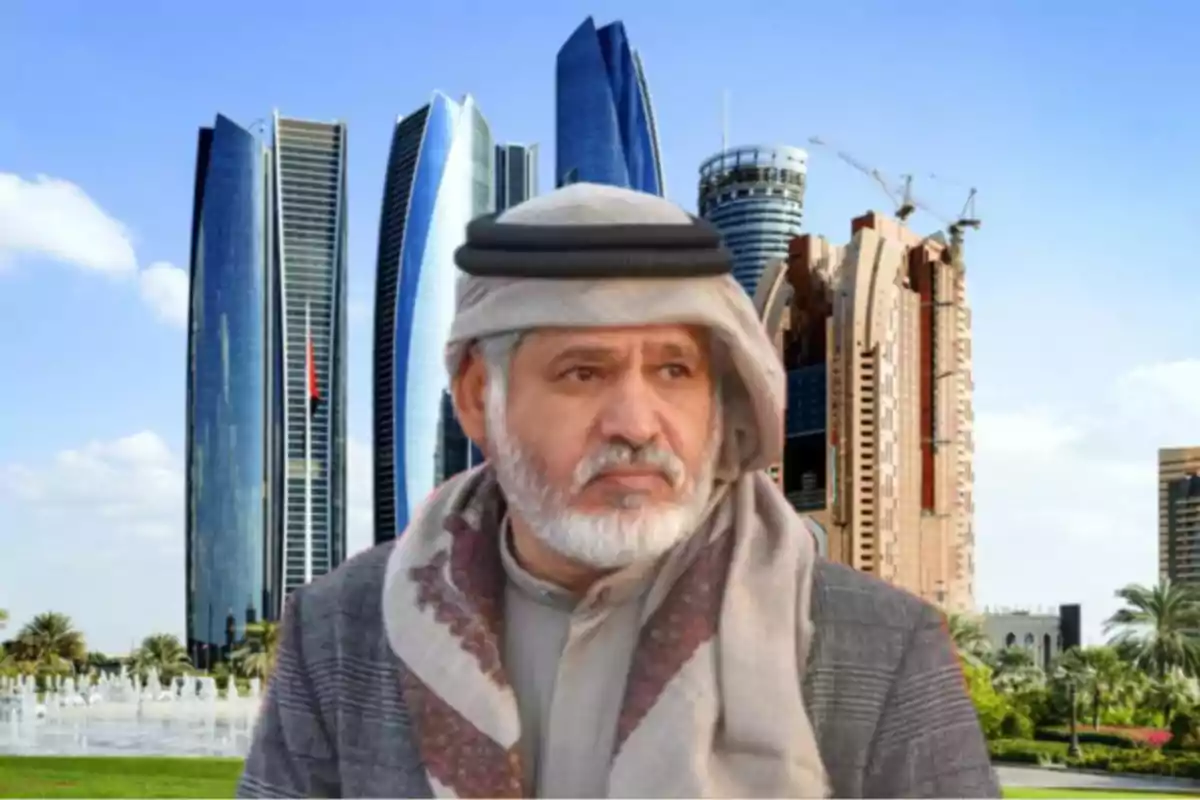 Hombre mayor con barba y vestimenta tradicional árabe posando frente a modernos rascacielos en una ciudad con cielo despejado