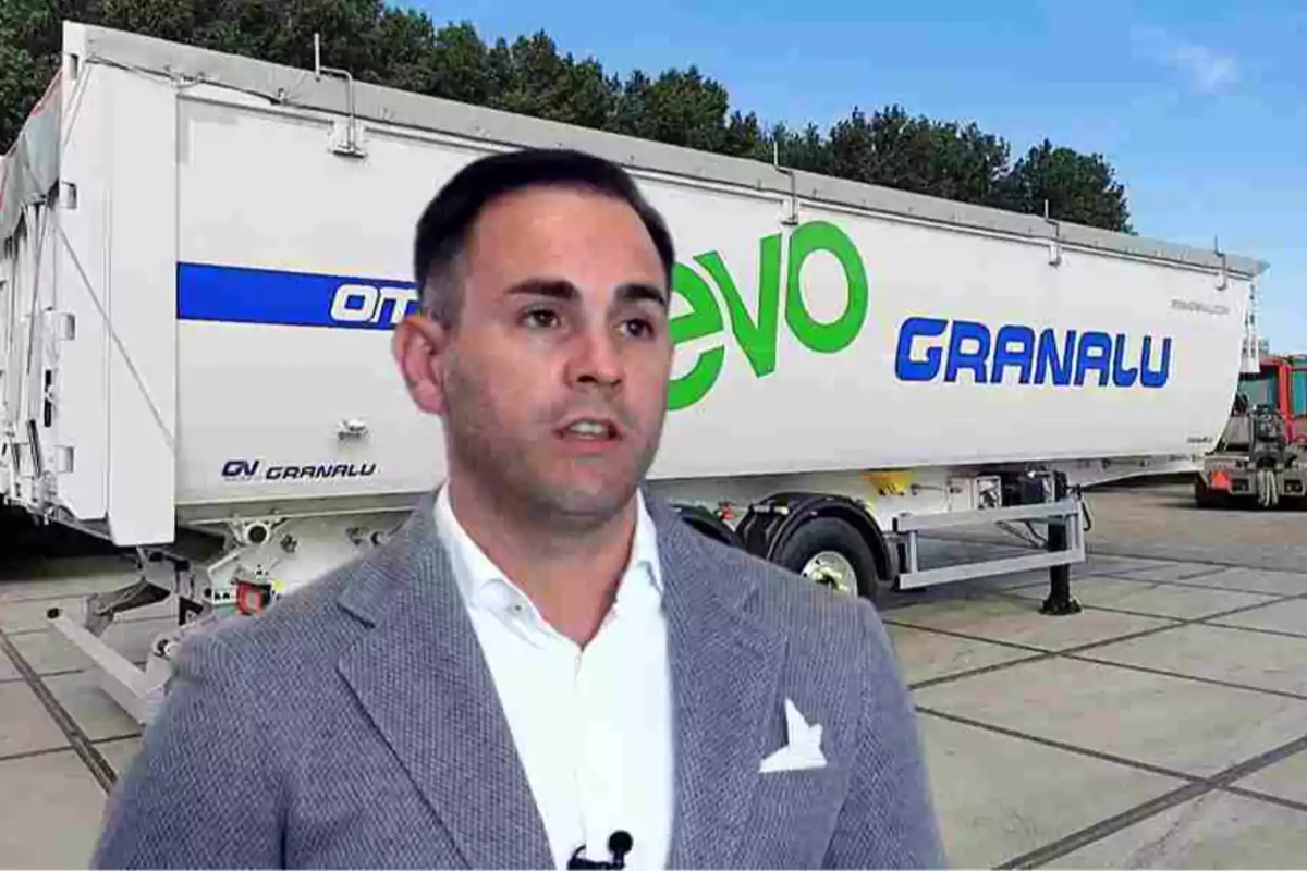 Hombre de traje gris posando frente a un remolque blanco con las palabras EVO y GRANALU en letras grandes