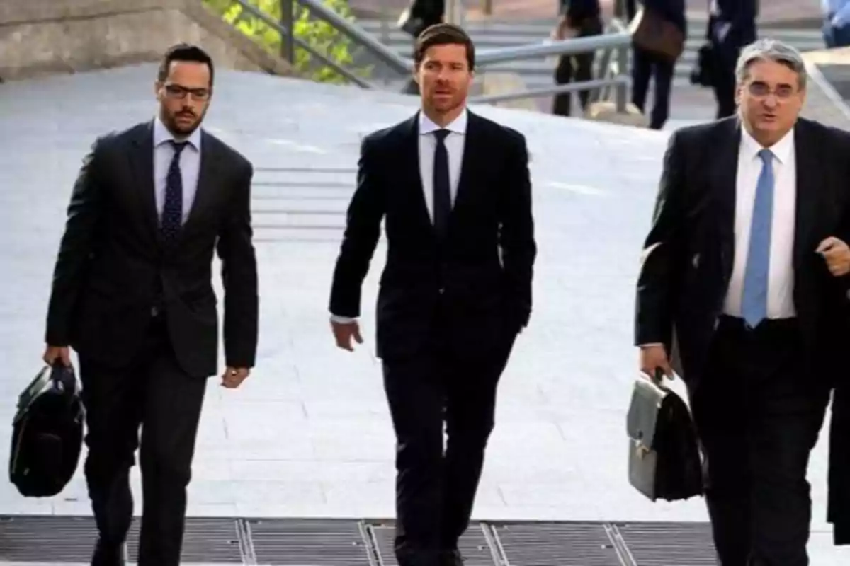 Tres hombres de negocios caminando juntos, vestidos con trajes formales y llevando maletines.