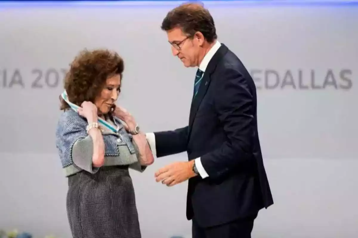 Una mujer recibe una medalla de manos de un hombre durante una ceremonia formal Una mujer recibe una medalla de manos de un hombre durante una ceremonia formal