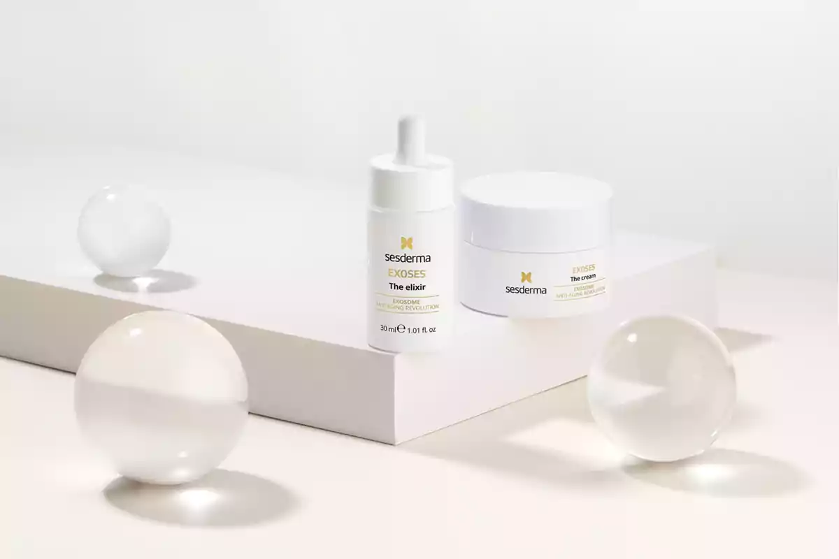 Productos de cuidado de la piel Sesderma Exoses sobre una superficie blanca con esferas de cristal alrededor.