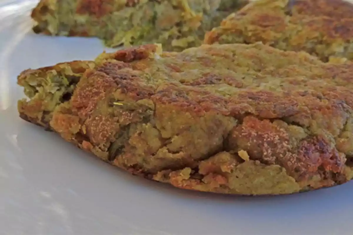 Una tortilla de color dorado con textura crujiente servida en un plato blanco.