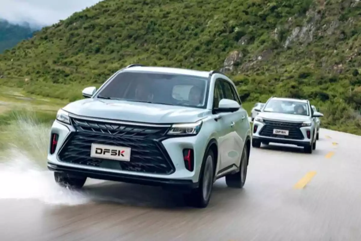 Dos SUVs de la marca DFSK circulando por una carretera rodeada de montañas y vegetación. Dos SUVs de la marca DFSK circulando por una carretera rodeada de montañas y vegetación.