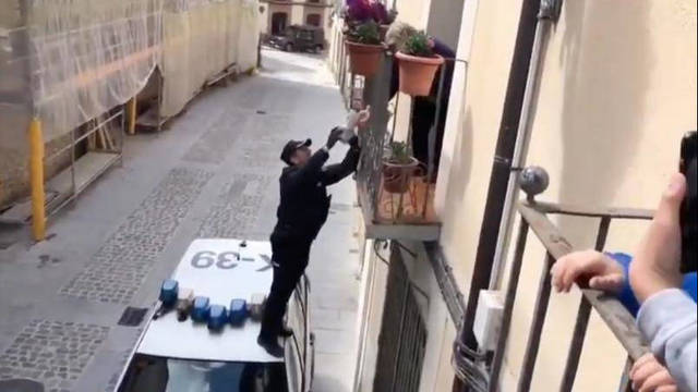 Un Policía llevando una tarta de cumpleaños a un balcón.