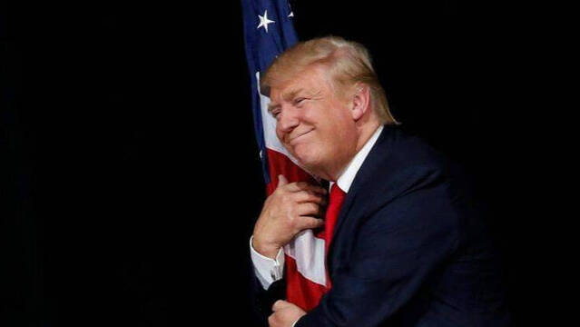 Trump agarrando la bandera americana.