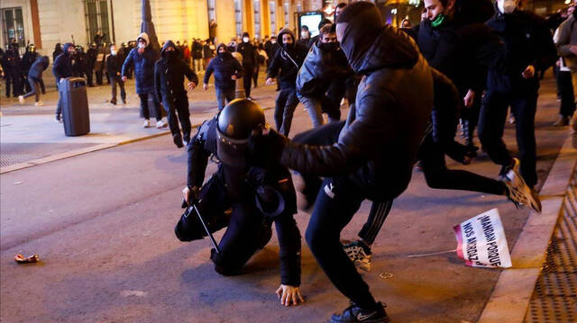 Policía siendo golpeado por un manifestante.