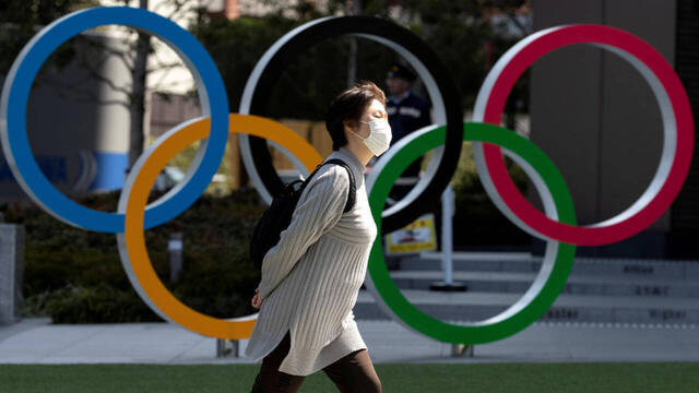 Ciudadana japonesa utilizando mascarilla junto al logo olímpico