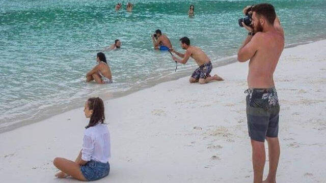 Personas haciéndose fotos en la orilla de una playa