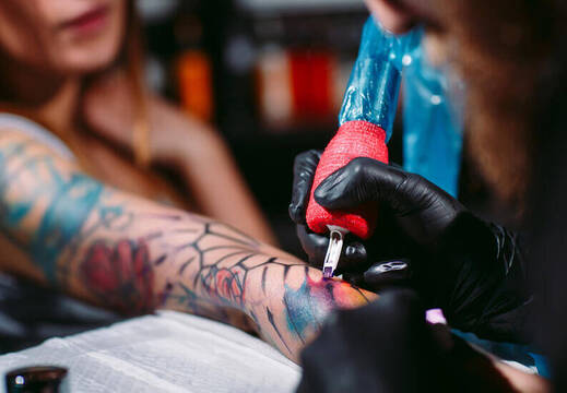Persona tatuándose a color.