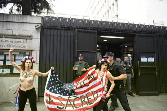 Miembros de Femen con una bandera de Estados Unidos siendo reprimidas por la policía.