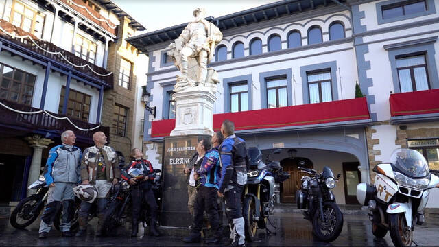 El equipo que recorrió la ruta de Elcano en moto, junto a una estatua del capitán.